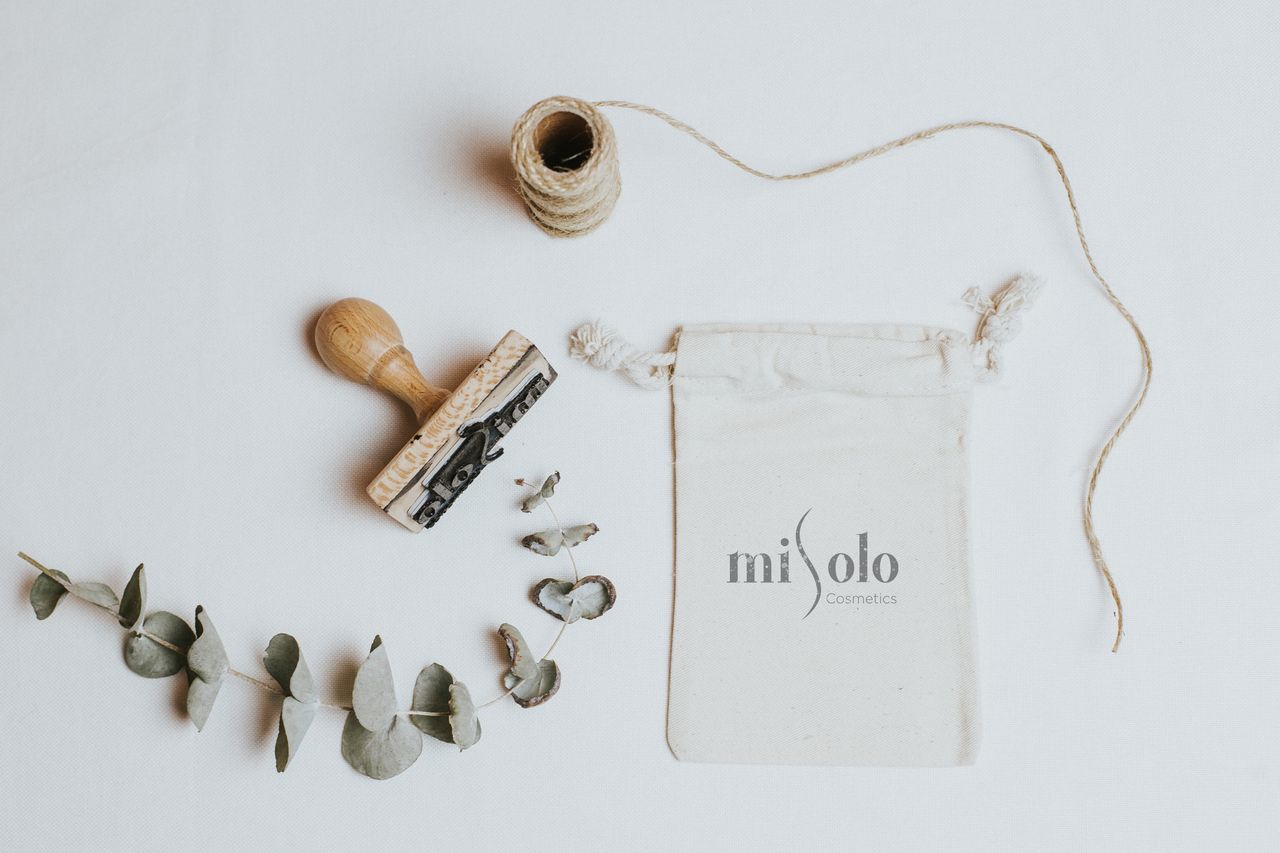 Packaging cosmétique bio avec des éléments naturels et un tampon sur fond blanc.